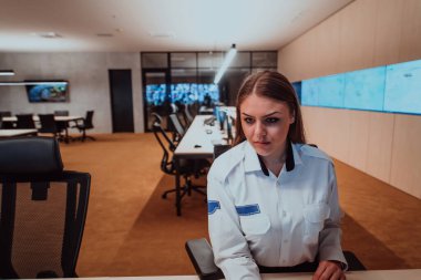 Veri kontrol odası ofislerinde çalışan kadın güvenlik operatörü. Çalışma istasyonunda birden fazla ekranla çalışan teknik operatör. Güvenlik görevlisi birden fazla monitör üzerinde çalışıyor.. 