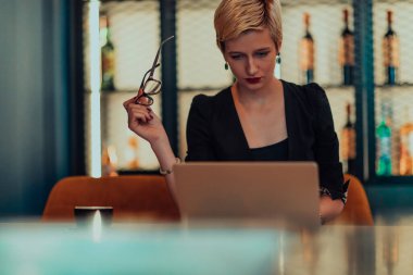 Businesswoman sitting in a cafe while focused on working on a laptop and participating in an online meetings. Selective focus