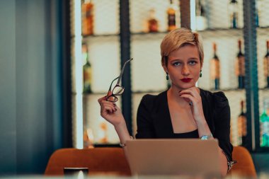 Businesswoman sitting in a cafe while focused on working on a laptop and participating in an online meetings. Selective focus