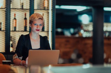 Businesswoman sitting in a cafe while focused on working on a laptop and participating in an online meetings. Selective focus