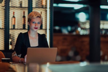 Businesswoman sitting in a cafe while focused on working on a laptop and participating in an online meetings. Selective focus