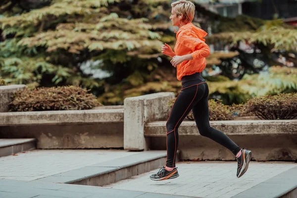 一个穿着运动服的金发姑娘正在城市里跑来跑去 火辣的金发美女保持着健康的生活方式 — 图库照片