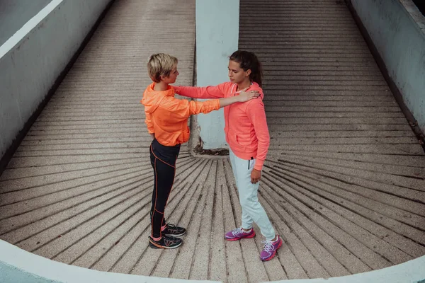 stock image Two women warming up together and preparing for a morning run in an urban environment. Selective focus . 