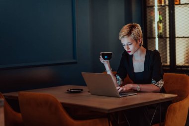 Businesswoman sitting in a cafe while focused on working on a laptop and participating in an online meetings. Selective focus