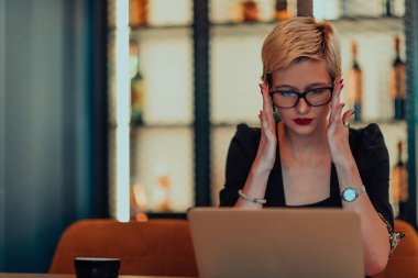 Businesswoman sitting in a cafe while focused on working on a laptop and participating in an online meetings. Selective focus