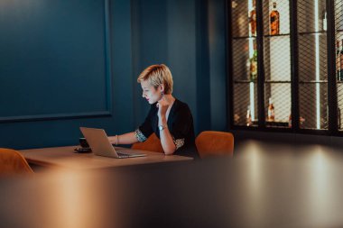 Businesswoman sitting in a cafe while focused on working on a laptop and participating in an online meetings. Selective focus