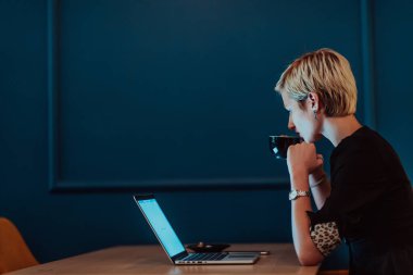 Businesswoman sitting in a cafe while focused on working on a laptop and participating in an online meetings. Selective focus