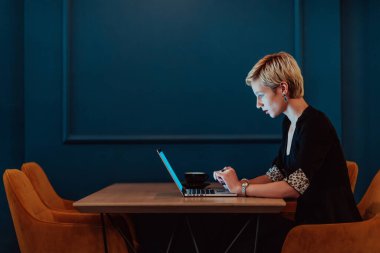 Businesswoman sitting in a cafe while focused on working on a laptop and participating in an online meetings. Selective focus