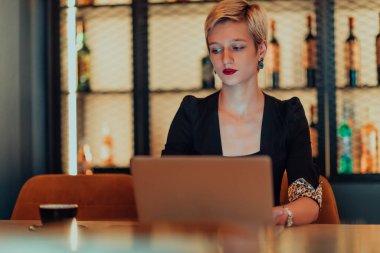 Businesswoman sitting in a cafe while focused on working on a laptop and participating in an online meetings. Selective focus