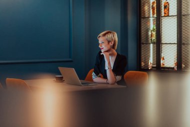 Businesswoman sitting in a cafe while focused on working on a laptop and participating in an online meetings. Selective focus
