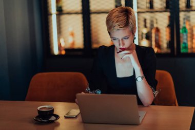 Businesswoman sitting in a cafe while focused on working on a laptop and participating in an online meetings. Selective focus