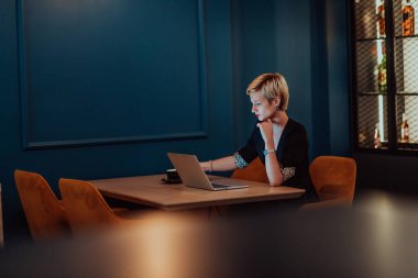 Businesswoman sitting in a cafe while focused on working on a laptop and participating in an online meetings. Selective focus