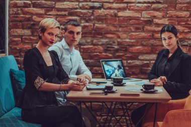 Happy businesspeople smiling cheerfully during a meeting in a coffee shop. Group of successful business professionals working as a team in a multicultural workplace. 