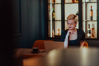 Businesswoman sitting in a cafe while focused on working on a laptop and participating in an online meetings. Selective focus