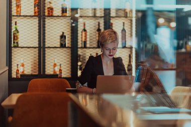 Businesswoman sitting in a cafe while focused on working on a laptop and participating in an online meetings. Selective focus