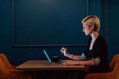 Businesswoman sitting in a cafe while focused on working on a laptop and participating in an online meetings. Selective focus