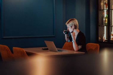 Businesswoman sitting in a cafe while focused on working on a laptop and participating in an online meetings. Selective focus