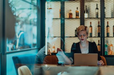 Businesswoman sitting in a cafe while focused on working on a laptop and participating in an online meetings. Selective focus