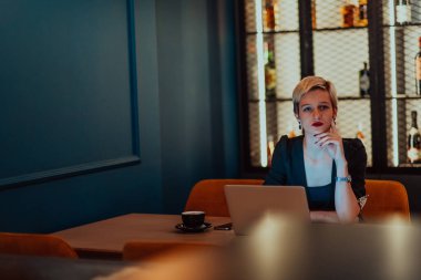 Businesswoman sitting in a cafe while focused on working on a laptop and participating in an online meetings. Selective focus