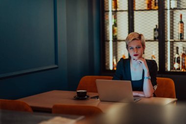 Businesswoman sitting in a cafe while focused on working on a laptop and participating in an online meetings. Selective focus