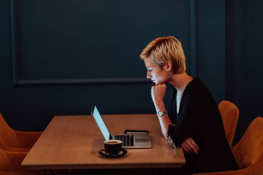 Businesswoman sitting in a cafe while focused on working on a laptop and participating in an online meetings. Selective focus