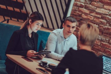 Happy businesspeople smiling cheerfully during a meeting in a coffee shop. Group of successful business professionals working as a team in a multicultural workplace. 