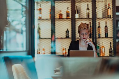 Businesswoman sitting in a cafe while focused on working on a laptop and participating in an online meetings. Selective focus