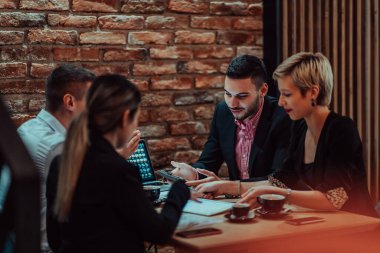 Happy businesspeople smiling cheerfully during a meeting in a coffee shop. Group of successful business professionals working as a team in a multicultural workplace. 