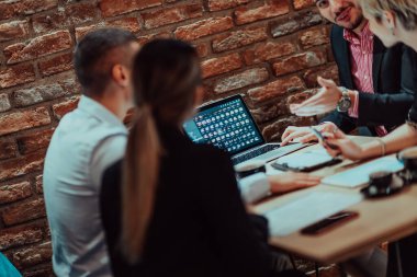 Happy businesspeople smiling cheerfully during a meeting in a coffee shop. Group of successful business professionals working as a team in a multicultural workplace. 