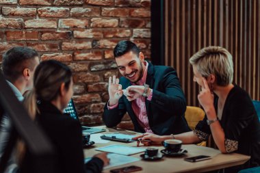 Happy businesspeople smiling cheerfully during a meeting in a coffee shop. Group of successful business professionals working as a team in a multicultural workplace. 