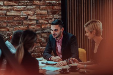 Happy businesspeople smiling cheerfully during a meeting in a coffee shop. Group of successful business professionals working as a team in a multicultural workplace. 