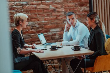 Happy businesspeople smiling cheerfully during a meeting in a coffee shop. Group of successful business professionals working as a team in a multicultural workplace. 