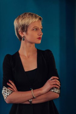 Blonde business woman, successful confidence with arms crossed on modern blue mat background. Selective focus. 