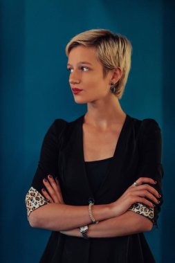 Blonde business woman, successful confidence with arms crossed on modern blue mat background. Selective focus. 