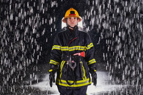 勇敢な救助任務で危険な雨の夜を通ってプロの制服を着た決定的な女性消防士は 彼女の絶え間ない勇気と命を救うというコミットメントを示しています — ストック写真