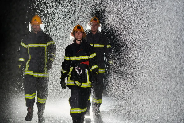 救助任務で雨の夜を行進するプロの消防士のグループ 彼らの揺るぎない勇気と不動の表現を反映した彼らの決定的な進歩と恐れを知らない表現 — ストック写真