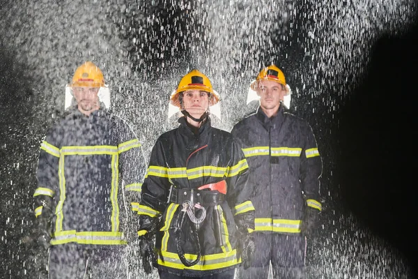 一队专业的消防员在雨夜中执行营救任务 他们坚定的步伐和无畏的表情反映了他们坚定不移的勇气和坚定不移的精神 — 图库照片