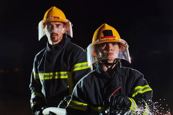 消防员使用水龙带以消除火警危险 执行危险救援任务的男女消防员小组 — 图库照片