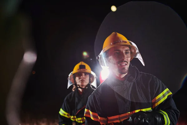 消防士は 火災の危険性を排除するために水ホースを使用して 危険な救助活動における女性と男性消防士のチーム — ストック写真