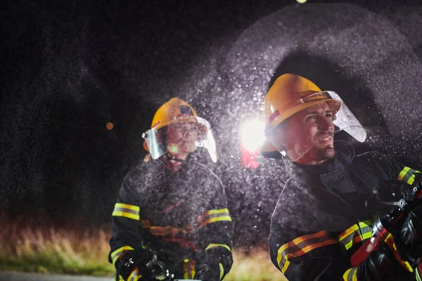 Palomiehet Käyttävät Vesiletkua Palovaaran Poistamiseen Nais Miespalomiesten Tiimi Vaarallisessa Pelastustehtävässä — kuvapankkivalokuva