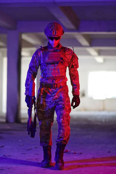 一名职业军人在一座由霓虹灯 蓝灯和紫灯照明的废弃建筑里执行着危险的任务 — 图库照片