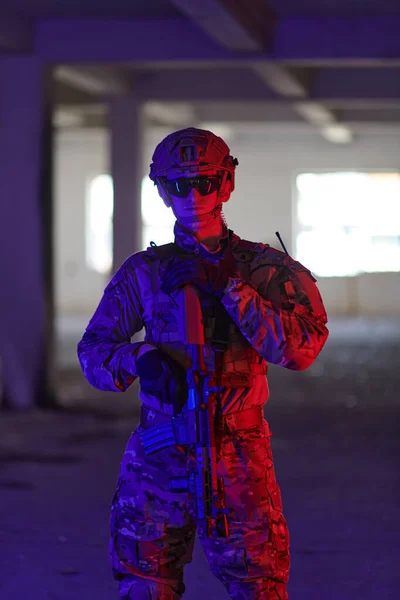 一名职业军人在一座由霓虹灯 蓝灯和紫灯照明的废弃建筑里执行着危险的任务 — 图库照片