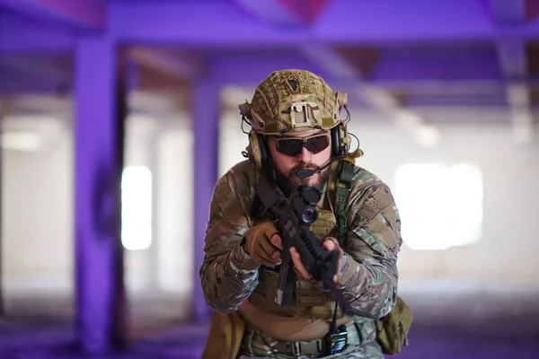 プロの兵士がネオンブルーと紫のライトに照らされた放棄された建物で危険な任務を遂行する — ストック写真
