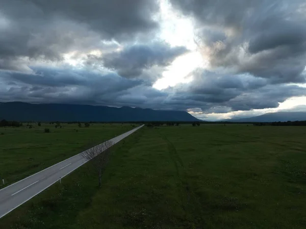 夏の曇りの日の間に美しい牧草地の自然界の空の田舎道の空中ショット — ストック写真