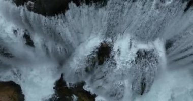 Bosna-Hersek 'te büyük bir şelaleyle vahşi nehrin destansı görüntüsünü oluşturan şaşırtıcı yavaş çekim. Kristal berrak içme suyu güzel şelale bulutlu yaz gününde.