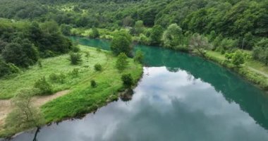 Bosna-Hersek 'te büyük bir şelaleyle vahşi nehrin destansı görüntüsünü oluşturan şaşırtıcı yavaş çekim. Kristal berrak içme suyu güzel şelale bulutlu yaz gününde.