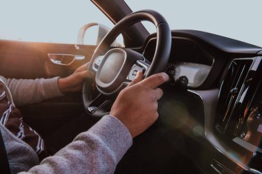 Gün batımında araba süren adamın elini kapat. Araba yolculuğu kavramı.