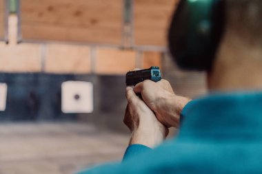 Korumalı kulaklık takan bir adam poligonda atış talimi yapıyor.. 
