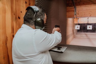 Korumalı kulaklık takan bir adam poligonda atış talimi yapıyor.. 