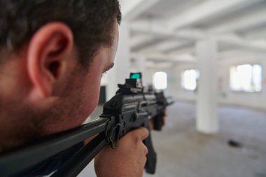  Terk edilmiş bir binada, bir terörist bir tüfekle askeri rakibine nişan alır. Bölgesel denetim için şiddetli bir savaşa girer. Çatışmanın tehlikelerini ve gerginliğini somutlaştırır.